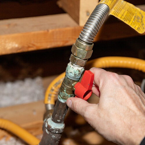 close-up of a worker adjusting a valve on a gas line